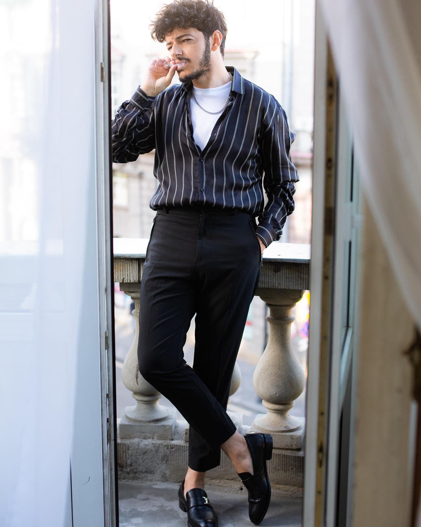 Αλέξανδρος Τσοποζίδης — πορτρέτο στο μπαλκόνι με ριγέ πουκάμισο